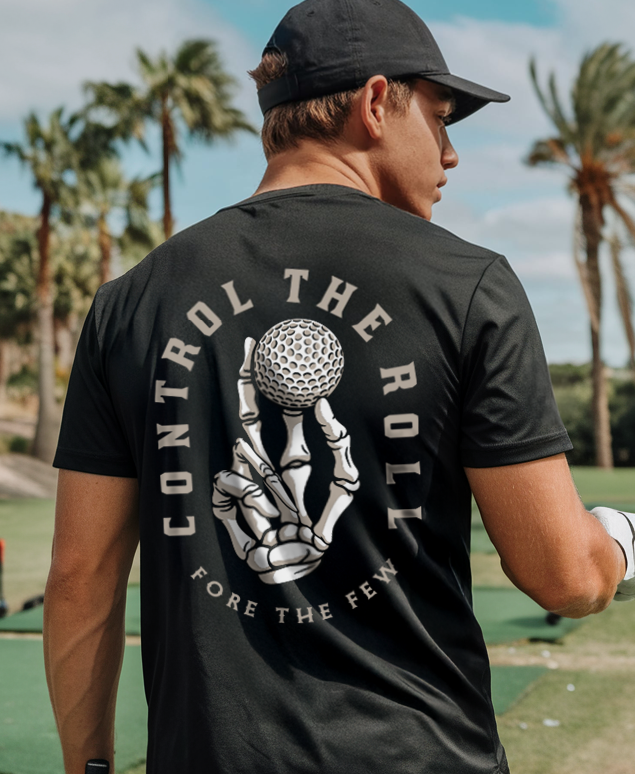 Man wearing a black t-shirt with a golf-themed design on a golf course with palm trees in the background.